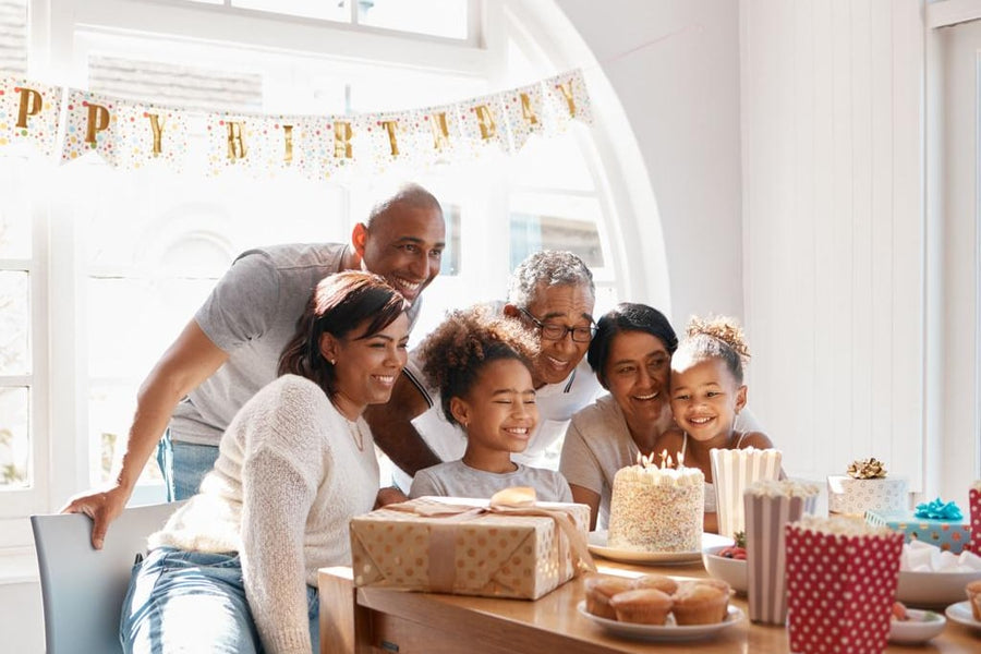 A family gathered around a birthday cake at a kitchen table